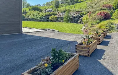 three wooden planters with plants on the side of a house at 5 Bedroom Lovely Home In Ølensvåg in Vaka