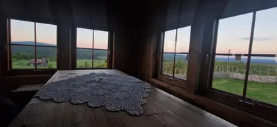 a room with windows and a table with a wine glass at Skotten Seter - Bed & Husky in Mork