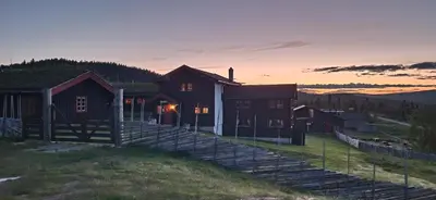 a house on a hill with a sunset in the background at Skotten Seter - Bed & Husky in Mork