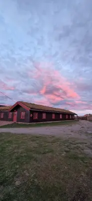 a large red barn with a cloudy sky in the background at Skotten Seter - Bed & Husky in Mork