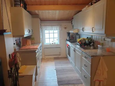 a large kitchen with white cabinets and a window at Idyllic lakeside cabin with private beach and boat in Vassli