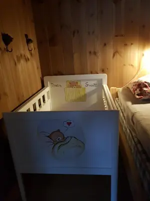 a white crib with two signs on it in a bedroom at Annex Fjara greater Oslos best view sleeps 10 guests in 3 bedrooms in Stange
