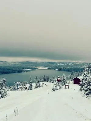 a snowy hill with a view of a lake at Snowcake Cottage in Sør-Fron