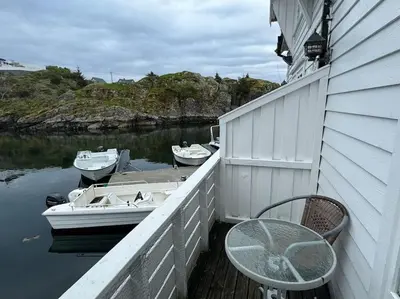 a balcony with a table and boats on the water at Nautnes Coastal Haven in Nautnes