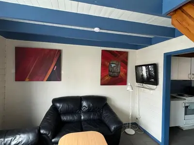 a living room with a black leather couch and paintings at Nautnes Coastal Haven in Nautnes