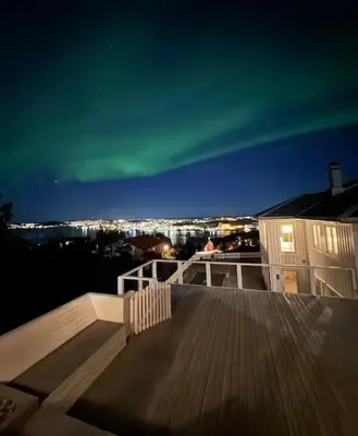 a deck with a view of a city at night at Villa Freya with stunning sea view in Kristiansund