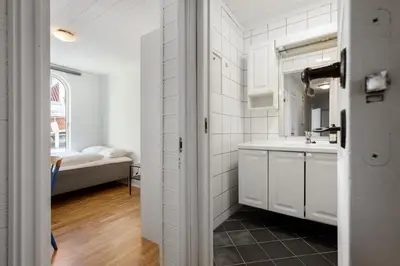 a white kitchen with a sink and a bed at City Center Apartment in Bergen