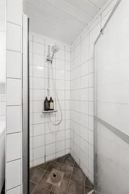 a shower in a bathroom with white tiled walls at City Center Apartment in Bergen