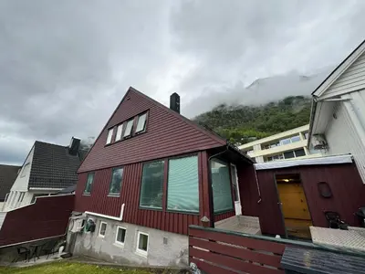 a red house with a mountain in the background at StarView Trolltunga Apartment in Odda