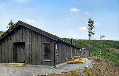 a large wooden building on a hill next to a forest at 3 Bedroom Amazing Home In Åfarnes in Åfarnes