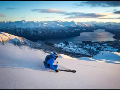 a person kneeling on a snow covered mountain with skis at Dalen Apartment in Stranda