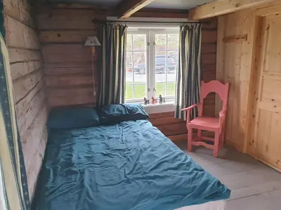 a bedroom with a bed and a chair and a window at Newly renovated house on a farm in Berge