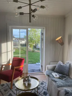 a living room with a couch and a table and a window at Koselig hus med stor og solrik hage in Lillehammer