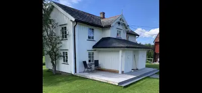 a white house with a porch and a chair at Rikstaddal in Kalvhagen
