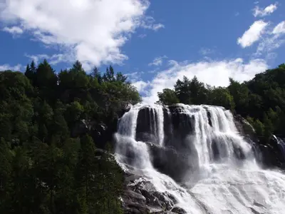 a waterfall in the middle of a forest at Fjordhytte-1 ist eine schöne Hütte bei Ænes am Hardangerfjord mit grandiosem Fjordpanorama, 20 PS Motorboot mietbar in Ænes