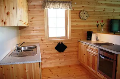 a kitchen with wooden walls and a sink and a window at Fjordhytte-4 nahe Trolltunga, Hardanger, direkt am Maurangerfjord in besonders attraktiver Umgebung in Sundal