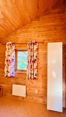 a room with a wooden wall with a window and a refrigerator at Fjordhytte-2 am Hardangerfjord, grandioses Fjordpanorama, 20 PS Motorboot mietbar! in Ænes