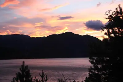 a sunset over a body of water with mountains at Fjordhytte-2 am Hardangerfjord, grandioses Fjordpanorama, 20 PS Motorboot mietbar! in Ænes