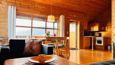a living room with a dining room table and a kitchen at Fjordhytte-2 am Hardangerfjord, grandioses Fjordpanorama, 20 PS Motorboot mietbar! in Ænes
