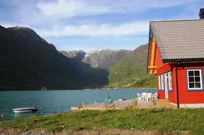 a red house and a boat on a lake at Fjordhytte-7, im Vestland, am Maurangerfjord beim Hardanger, nahe Trolltunga, zwischen Odda und Rosendal in Sundal
