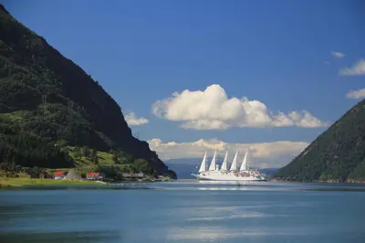 a large cruise ship in a lake between two mountains at Fjordhytte-7, im Vestland, am Maurangerfjord beim Hardanger, nahe Trolltunga, zwischen Odda und Rosendal in Sundal