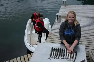 a group of people on a dock with a bunch of fish at Fjordhytte-7, im Vestland, am Maurangerfjord beim Hardanger, nahe Trolltunga, zwischen Odda und Rosendal in Sundal