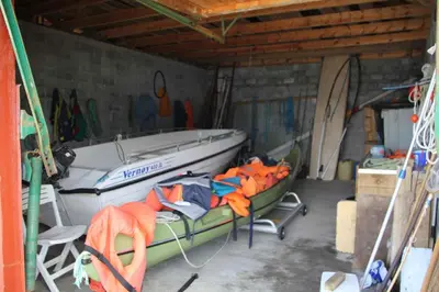 a boat in a garage with a table and a chair at Fjordhytte-41 mit mietbarem 9,9 PS Motorboot am Hardangerfjord in Rosendal