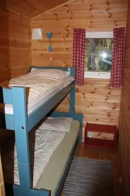 two bunk beds in a log cabin with a window at Fjordhytte-39 am Hardangerfjord, Motorboot mietbar in Rosendal