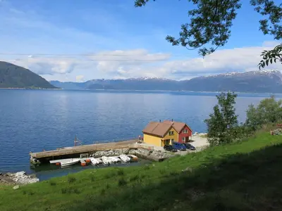 a house on a dock in the middle of a lake at Fjordhytte-16 direkt am Sognefjord in Bjordal, mit mietbaren 9,9 PS bis 60 PS Motorbooten in Bjordal