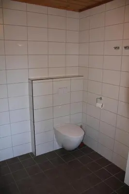 a bathroom with a toilet in a tiled room at Fjordhytte-6 direkt am Maurangerfjord, einem Seitenarm des Hardangerfjords in Sundal