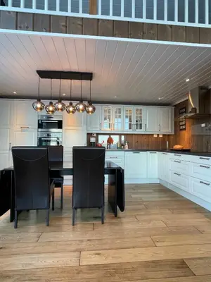 a kitchen with white cabinets and a table and chairs at Fjordhytte-13 in Ænes