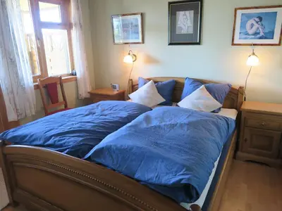 a bed with blue sheets in a room with a window at Fjordhytte-36 in Bøvågen