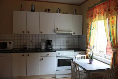 a kitchen with white cabinets and a table and a window at Fjordhytte-17 in Norwegen direkt am Fjord, mit mietbaren 9,9 PS bis 60 PS Motorbooten in Bjordal