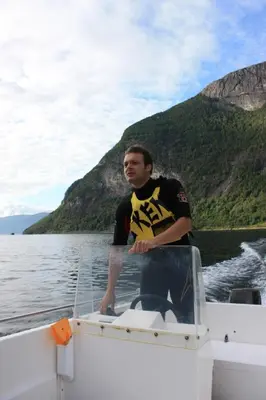 a man standing on the front of a boat on the water at Fjordhytte-17 in Norwegen direkt am Fjord, mit mietbaren 9,9 PS bis 60 PS Motorbooten in Bjordal
