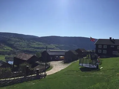 a playground on a hill with a house at Rudland Gård - Unik gårdsovernatting i stabbur fra 1750 in Sør-Fron