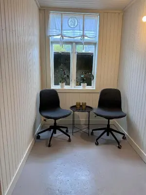 two chairs and a table in a room with a window at Villa Utsikten Eggen in Åndalsnes