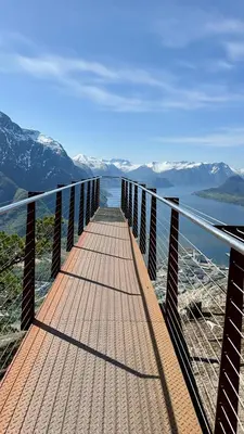 a bridge over a body of water with snow covered mountains at Villa Utsikten Romsdalen in Åndalsnes