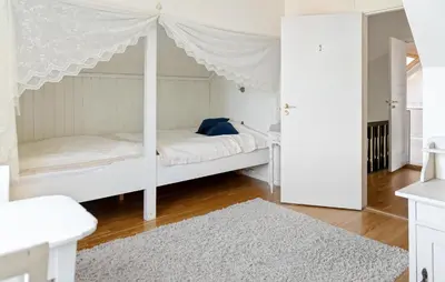 a bedroom with a white canopy bed with a white rug at Doktorgarden in Selje