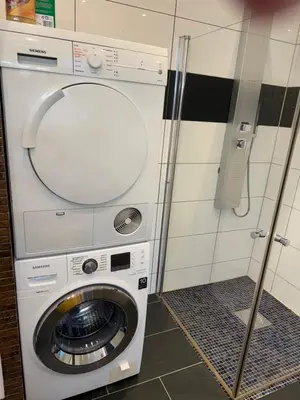 a washing machine in a bathroom with a phone at Duży apartament w centrum in Ålesund