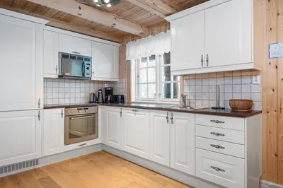 a white kitchen with wooden ceilings and white cabinets at Trysilfjell sør 825 in Trysil