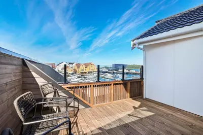 a balcony with chairs and a view of a harbor at Florø Apartments Hotell in Florø