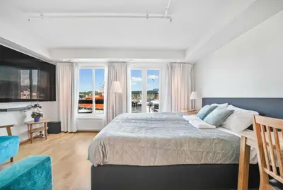 a bedroom with a large bed and a balcony at Florø Apartments Hotell in Florø