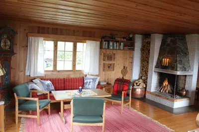a living room with a table and a fireplace at Jonstølen by Norgesbooking - cabin at 1020 masl in Trondsgard
