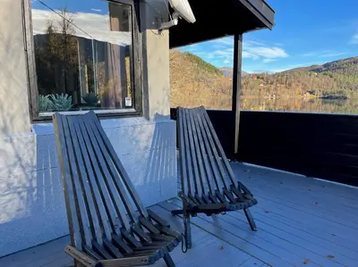 two benches sitting on a porch looking out at a lake at Cozy cabin with a view in Kvamseter