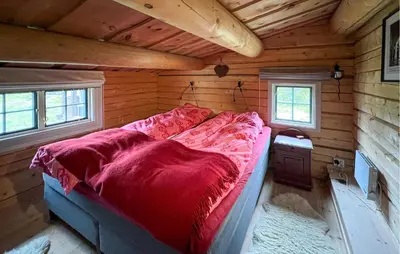 a bed in a log cabin with a red blanket at Awesome Home In Aurdal With Sauna in Aurdal