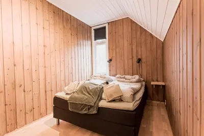 a bedroom with a bed in a room with wooden walls at Toppleilighet i sentrum av Lillehammer in Lillehammer