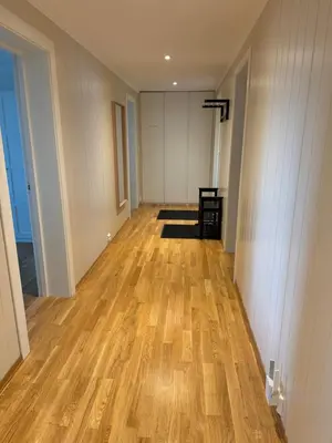 an empty hallway with wood floors and white walls at Charming 3-Bedroom Apartment in the Heart of Kristiansund in Kristiansund