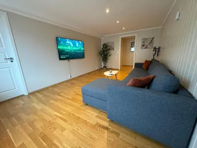 a living room with a blue couch and a flat screen tv at Charming 3-Bedroom Apartment in the Heart of Kristiansund in Kristiansund