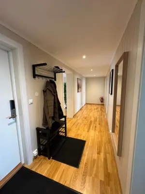 a hallway with a room with a staircase and a room with wooden floors at Charming 3-Bedroom Apartment in the Heart of Kristiansund in Kristiansund