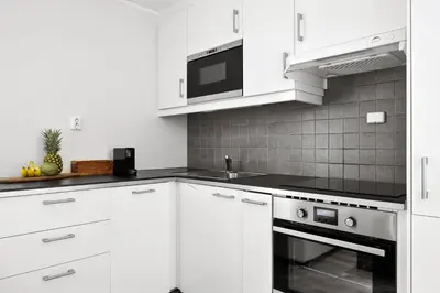 a white kitchen with white cabinets and a microwave at Pergola - Free parking - 5 min walk to facilities in Bergen